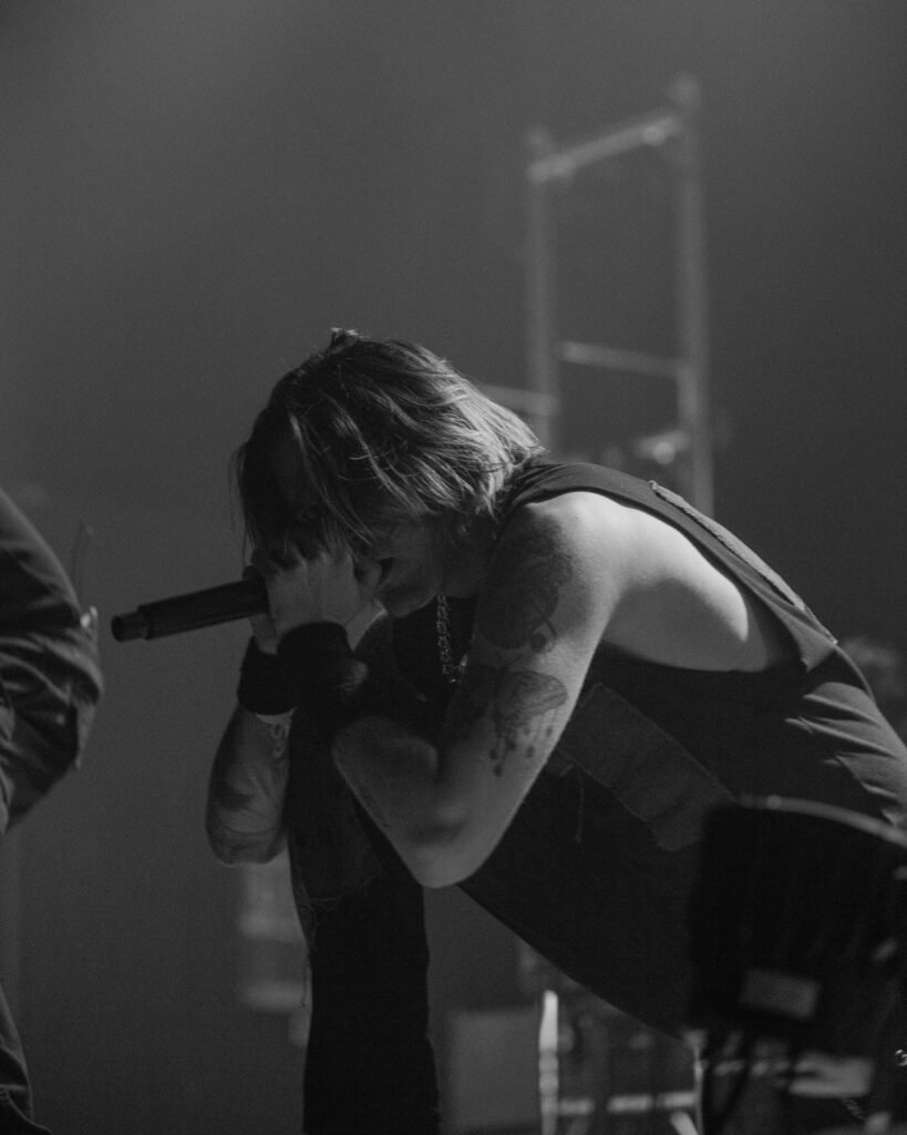 Black-and-white photograph of a performer leaning forward towards a microphone