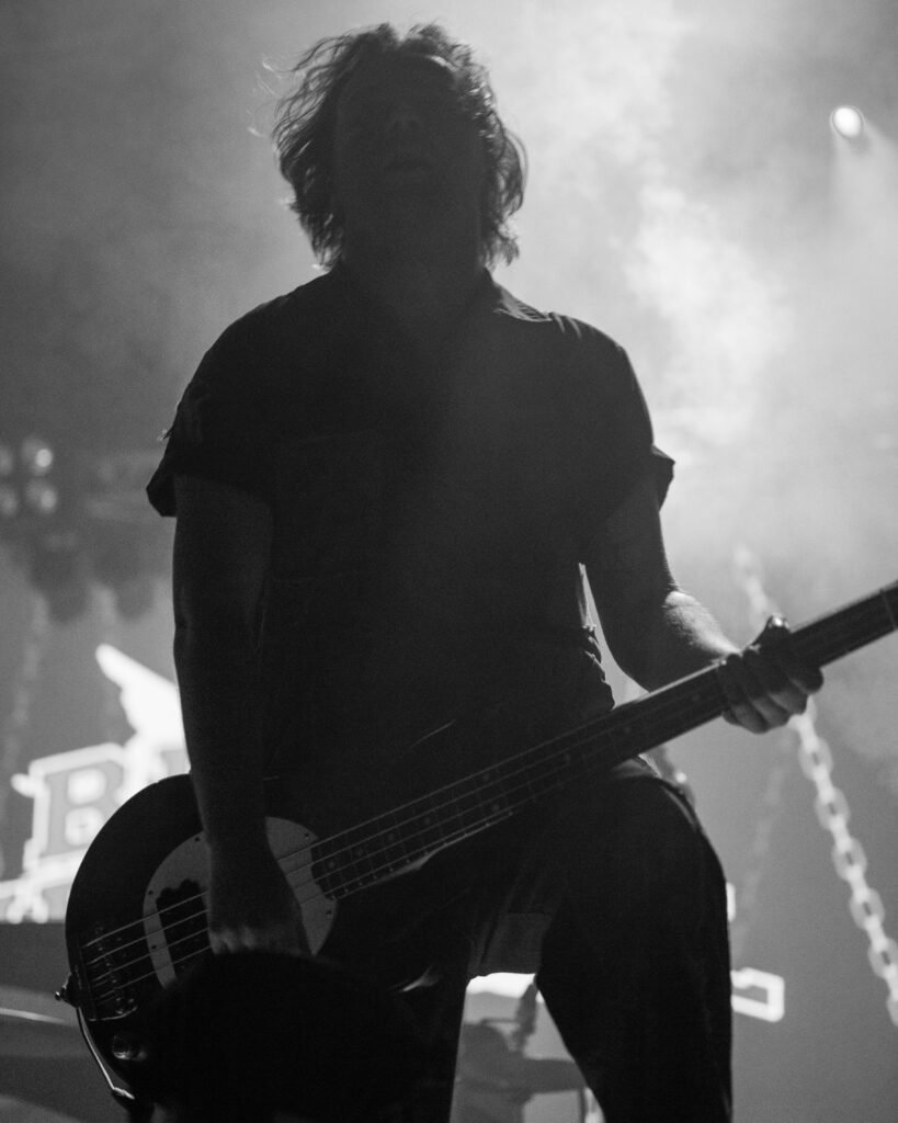 Black-and-white silhouette of a guitarist beneath stage lights