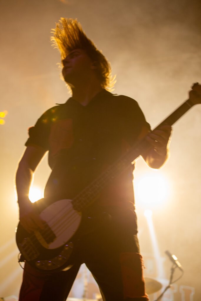 Guitarist silhouetted against warm golden stage lighting