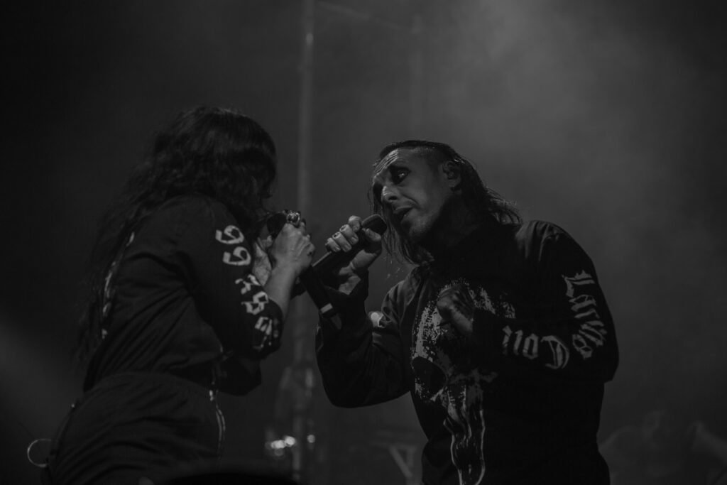 Two vocalists facing each other on a dark stage