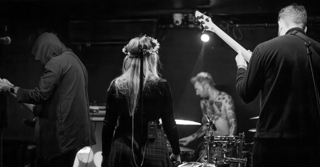 Black-and-white view from behind the musicians, looking towards the drummer